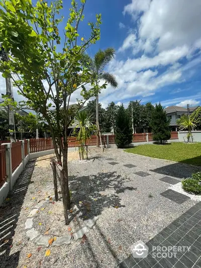 Spacious garden with lush greenery and clear blue sky in a serene residential area.