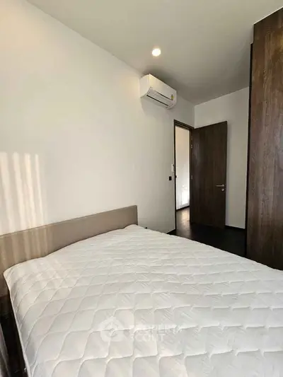 Modern bedroom with air conditioning and minimalist design, featuring a comfortable bed and sleek wooden accents.