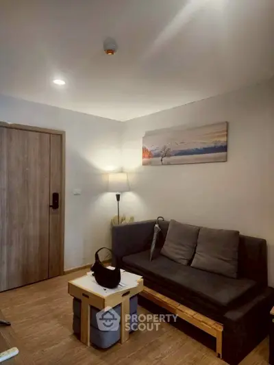 Cozy living room with modern decor and wooden flooring, featuring a comfortable sofa and stylish lighting.