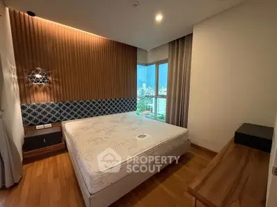 Modern bedroom with wooden flooring and large window offering city view.