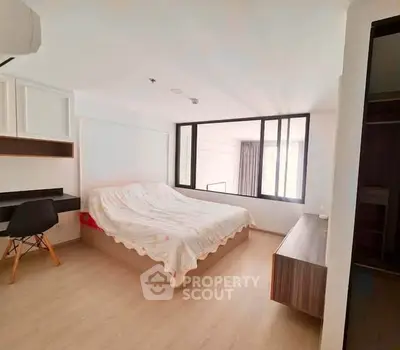 Spacious bedroom with modern decor and natural light in a stylish apartment.