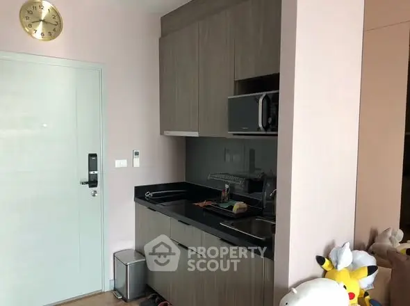 Compact kitchen with modern cabinetry and microwave in cozy apartment.