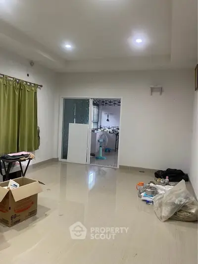 Spacious living room with tiled flooring and sliding glass doors leading to a modern kitchen.