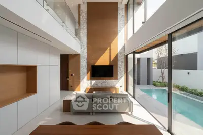 Luxurious modern living room with high ceilings and pool view, featuring sleek design and abundant natural light.