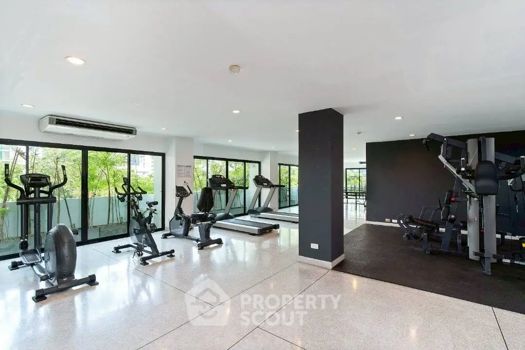 Spacious modern gym with large windows and fitness equipment in a residential building.