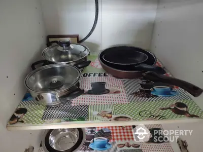 Organized kitchen cabinet with pots and pans on decorative shelf liner.