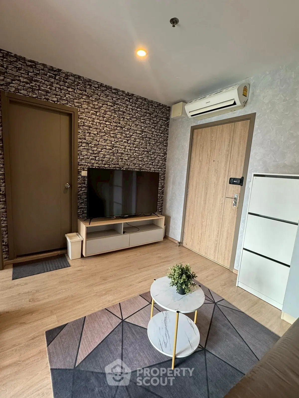 Modern living room with stylish decor and flat-screen TV, featuring wood flooring and contemporary design.