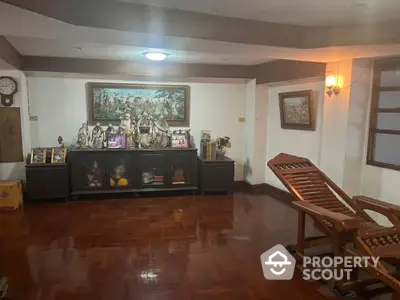 Spacious living room with polished hardwood floors and traditional decor, featuring a large wooden console and classic artwork.