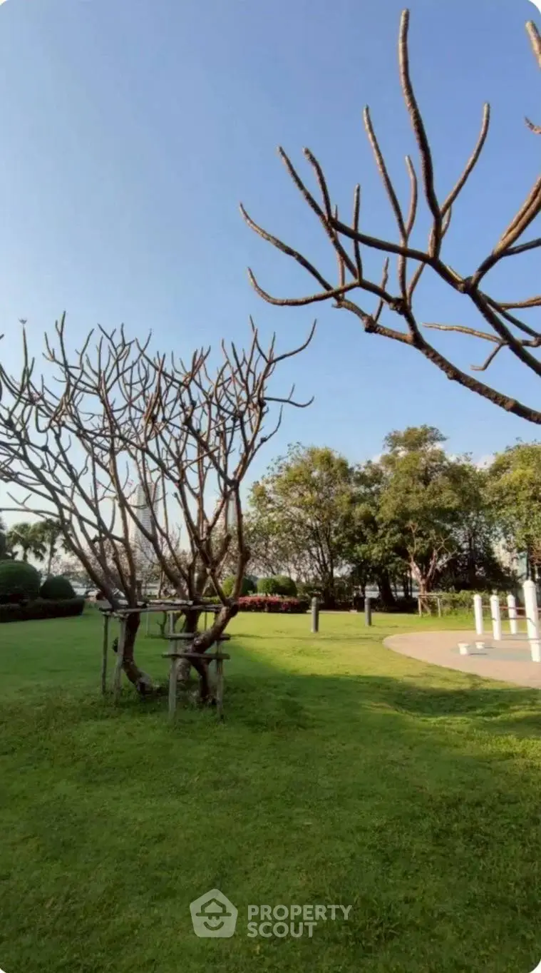 Lush green garden with trees under a clear blue sky, perfect for relaxation.