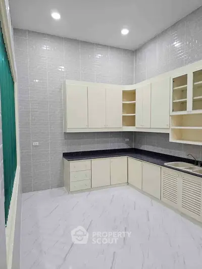Modern kitchen with sleek cabinetry and tiled walls, featuring ample storage and counter space.