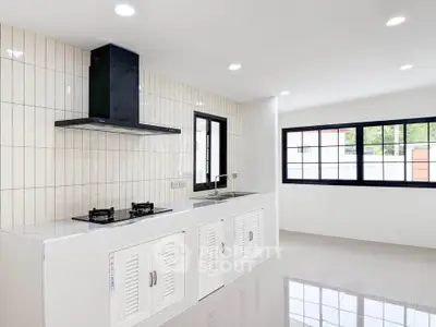 Modern kitchen with sleek design, featuring gas stove and ample natural light.