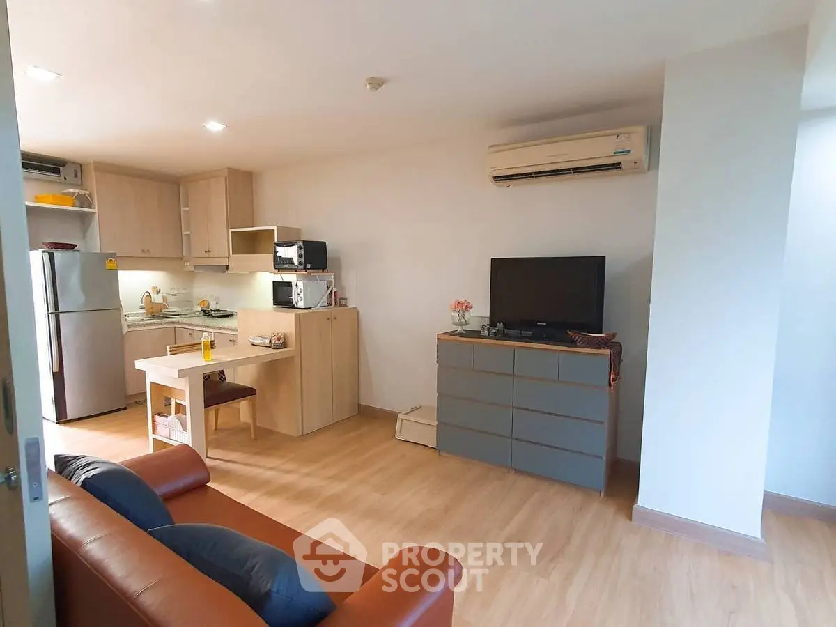 Modern open-plan living room with kitchen, featuring sleek furniture and wooden flooring.