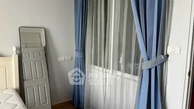 Cozy bedroom with elegant blue curtains and a stylish mirror, perfect for a serene retreat.
