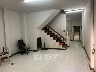 Spacious interior with staircase and tiled flooring, ideal for renovation or customization.