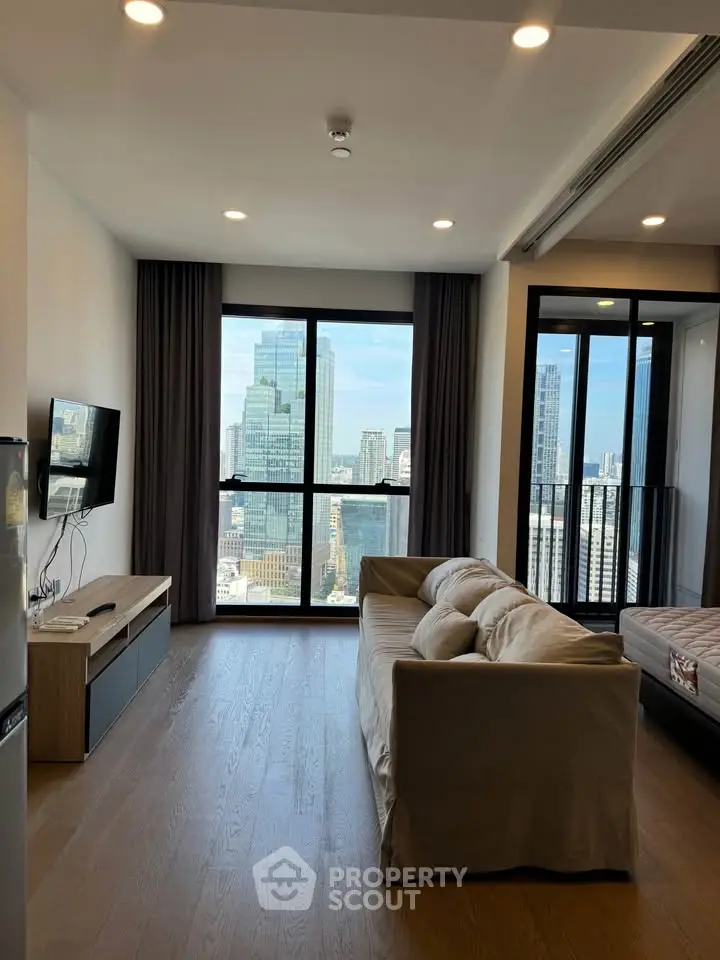 Modern living room with city view, featuring a cozy sofa and sleek TV setup, perfect for urban living.