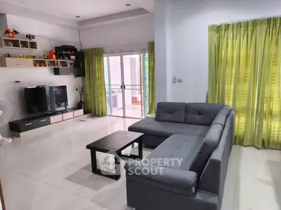 Spacious living room with modern sofa and entertainment center, bright natural light and green curtains.