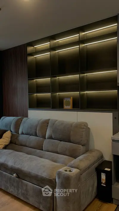 Modern living room with plush gray sofa and stylish illuminated shelving