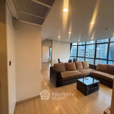 Spacious living room with modern furniture and large windows offering city views.