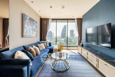 Luxurious living room with stunning city view, modern blue sofa, elegant decor, and large TV setup.