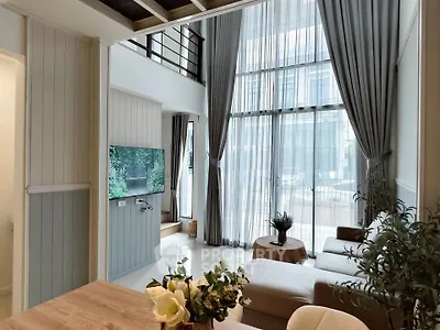 Spacious modern living room with high ceilings and large windows, featuring elegant decor and abundant natural light.