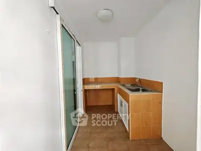 Compact kitchen with tiled backsplash and sliding glass door in modern apartment.