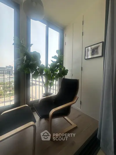 Cozy corner with modern chair and large windows offering city view, perfect for relaxation.