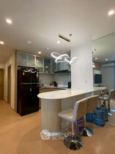 Modern kitchen with island, stylish lighting, and sleek appliances in a contemporary apartment.