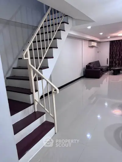 Spacious modern living room with sleek staircase and comfortable seating area.