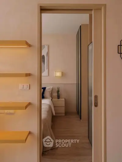 Cozy bedroom with modern design and warm lighting, featuring a sliding door and stylish shelving.