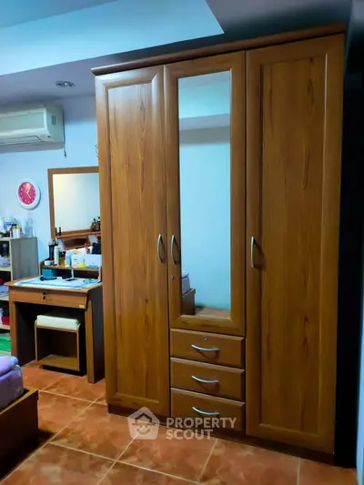 Spacious bedroom with wooden wardrobe and vanity set, perfect for stylish storage solutions.