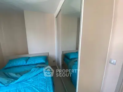 Cozy bedroom with mirrored wardrobe and blue bedding, perfect for modern living.