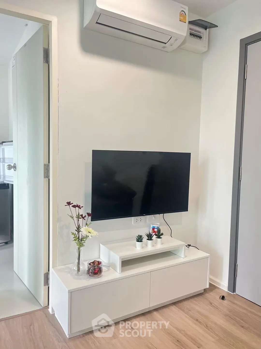 Modern living room with wall-mounted TV and sleek white furniture