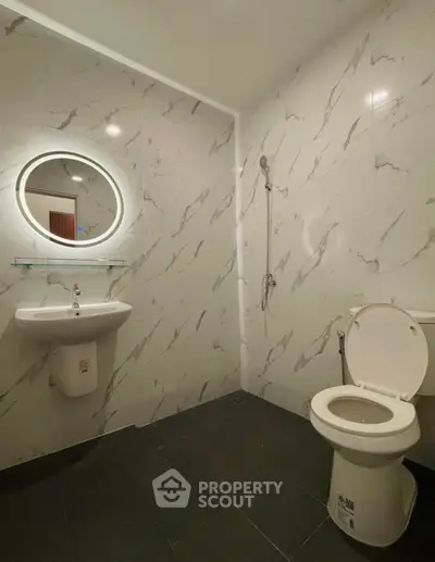 Modern bathroom with sleek marble walls and minimalist fixtures.