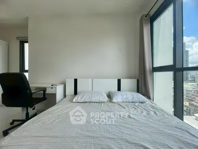 Modern bedroom with city view, featuring a sleek desk and comfortable bed in a bright, airy space.