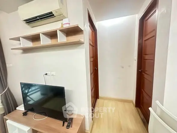 Modern apartment interior with TV, air conditioning, and wooden doors in a cozy hallway.