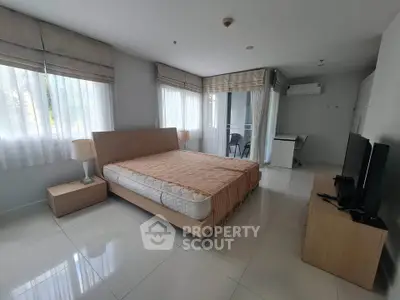 Spacious bedroom with modern furnishings and large windows in a bright apartment.