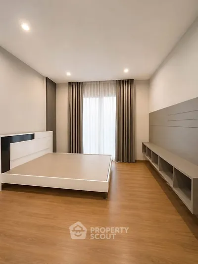 Spacious modern bedroom with wooden flooring and large window
