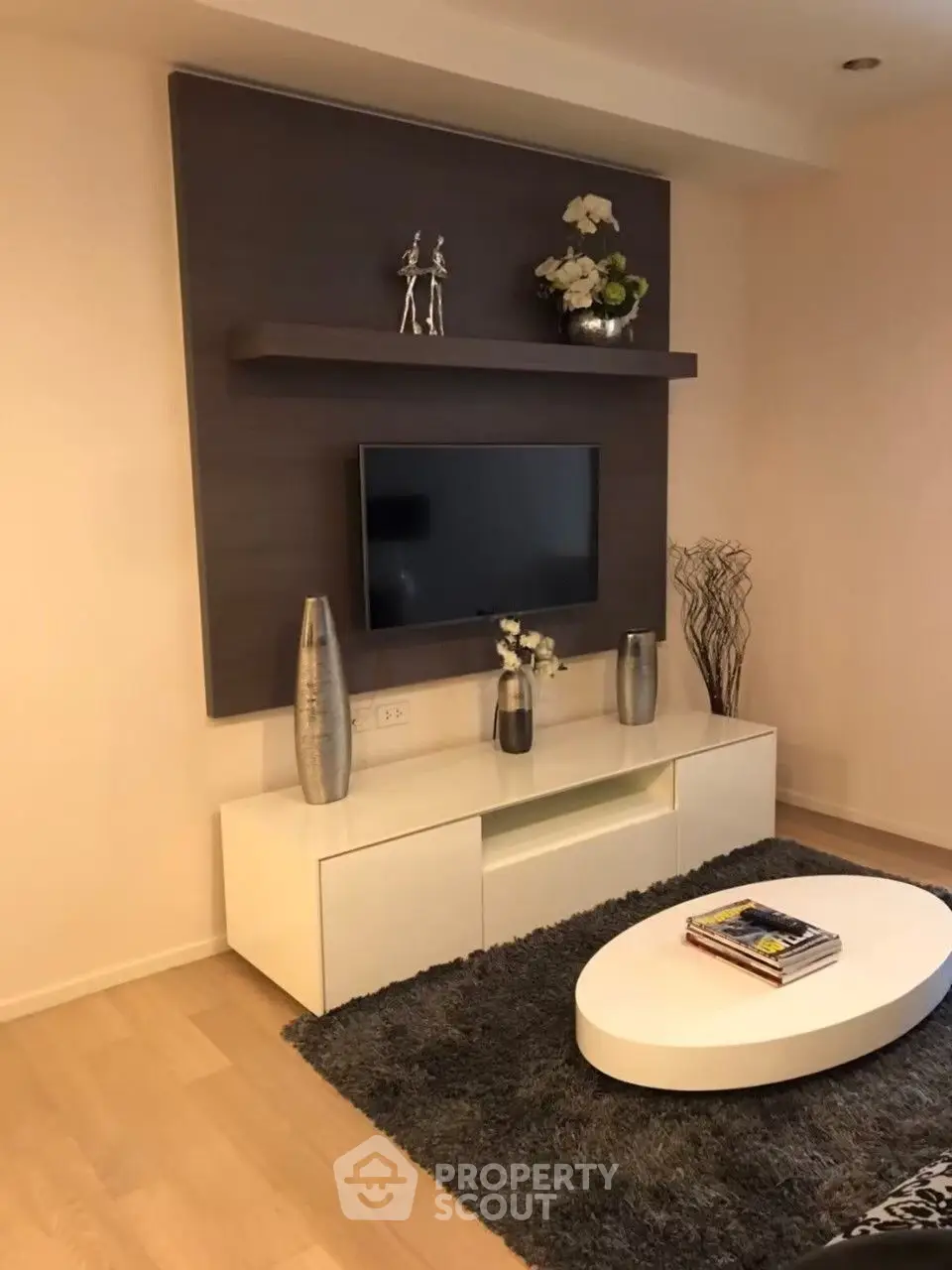 Modern living room with stylish decor and mounted TV, featuring sleek furniture and elegant accents.