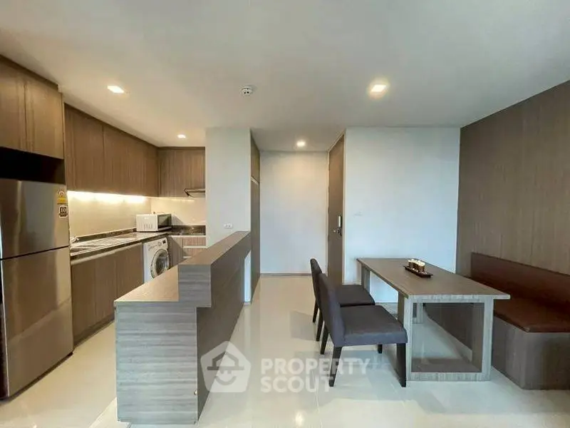 Modern kitchen with sleek design and dining area in open layout apartment.