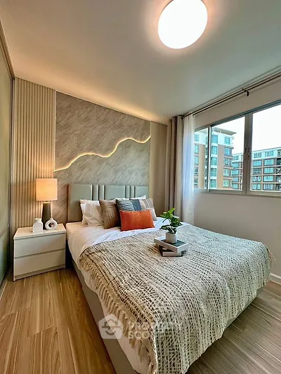 Modern bedroom with stylish decor and large window offering city views.