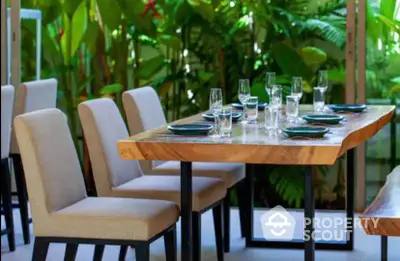 Elegant outdoor dining area with lush greenery and stylish wooden table setting.