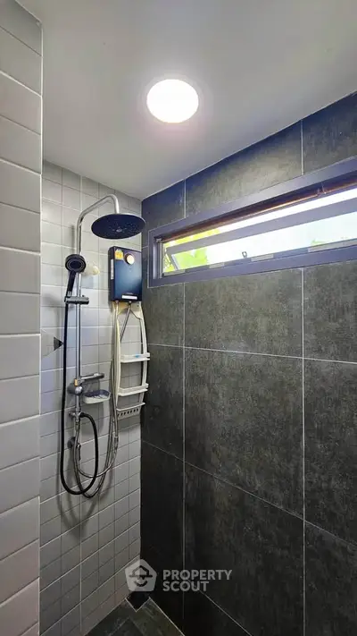 Modern bathroom with sleek shower fixtures and natural light from window.