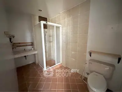 Spacious bathroom with shower and tiled flooring in modern home.
