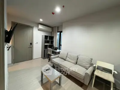 Modern living room with cozy sofa, wall-mounted TV, and study area in a stylish apartment.