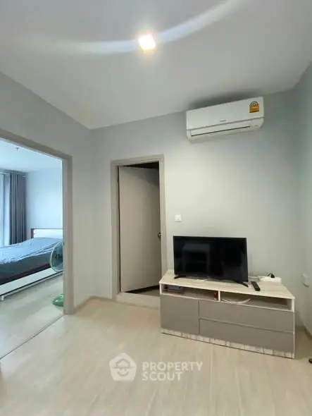 Modern apartment interior with TV and air conditioning, featuring a glimpse into a cozy bedroom.