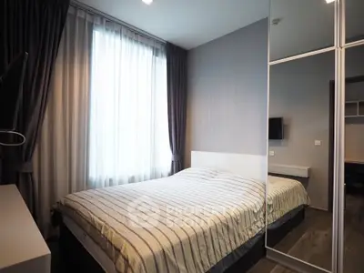 Modern bedroom with striped bedding and mirrored wardrobe in stylish apartment.