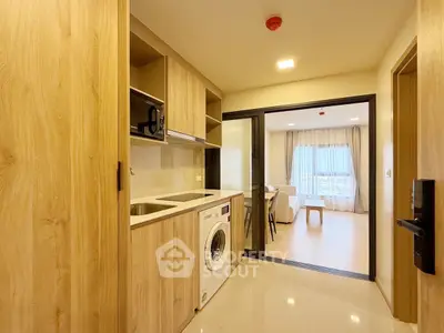 Modern kitchen with washing machine and open layout leading to bright living room.