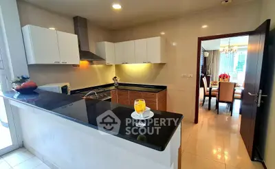 Modern kitchen with sleek black countertops and open layout leading to elegant dining area.