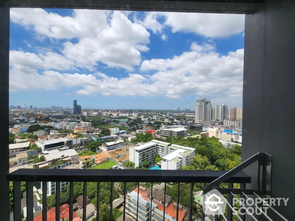 Stunning cityscape view from a high-rise balcony with clear blue skies and lush greenery.