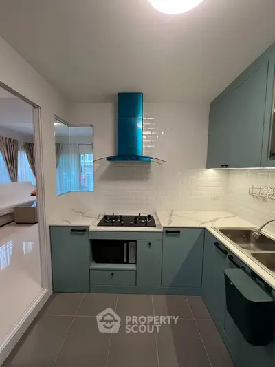 Modern kitchen with teal cabinets, gas stove, and sleek design